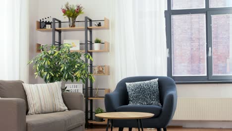 Man-Placing-Table-and-Drinking-Coffee-at-Home.household,-home-improvement-and-interior-concept--happy-smiling-young-man-placing-table-in-front-of-armchair-and-drinking-coffee