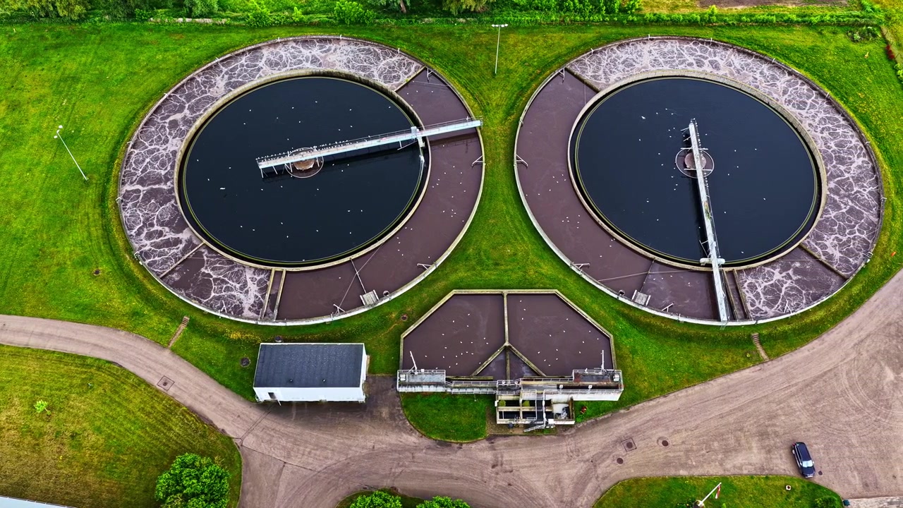 Aerial view of large circular water treatment tanks at a facility surrounded by grass