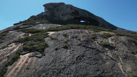 Drone-ascending-over-rocky-slope-mountain-toward-cave-on-top-of-Frenchman-Mount,-National-Park-near-Esperance,-Western-Australia