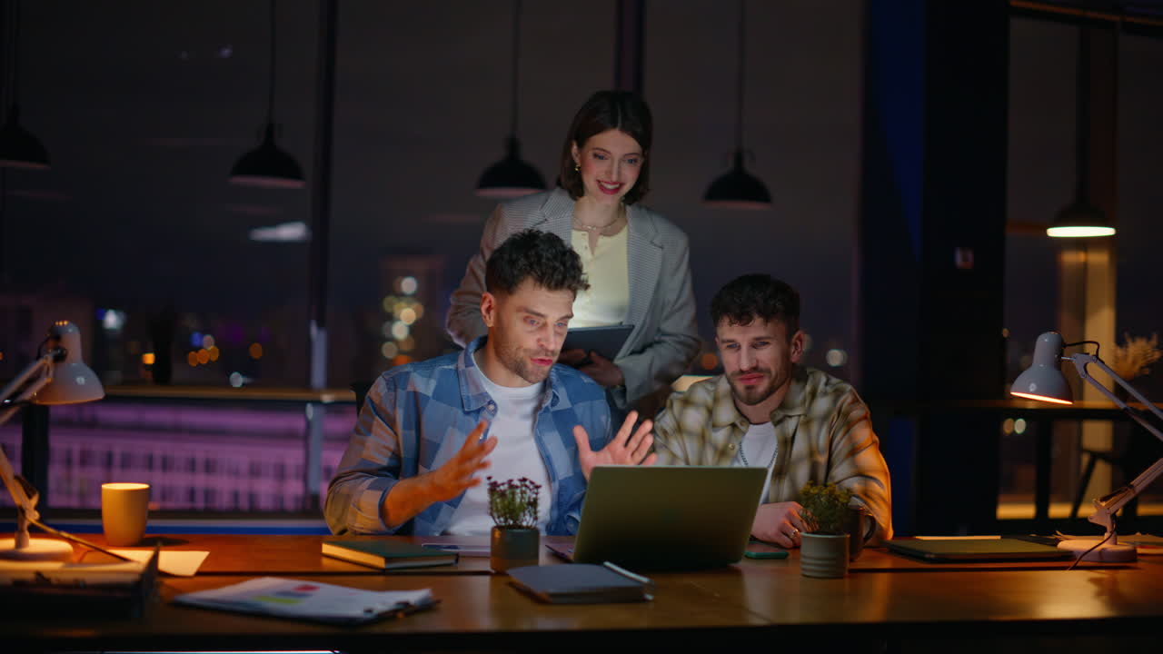 Evening teammates videocalling laptop in modern panoramic workplace closeup