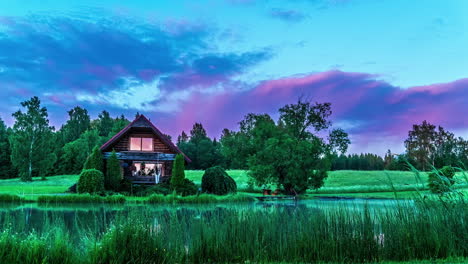 Time-lapse-of-illuminated-clouds-flying-over-charming-wooden-cottage-on-pond