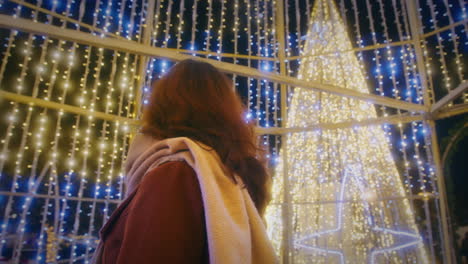 girl looking at lights of a christmas market tree slow motion rotating gimbal shot