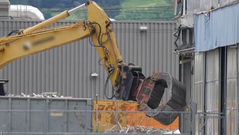 Excavadora-Con-Garra-Hidráulica-Desmantelando-Un-Gran-Edificio-En-Suiza