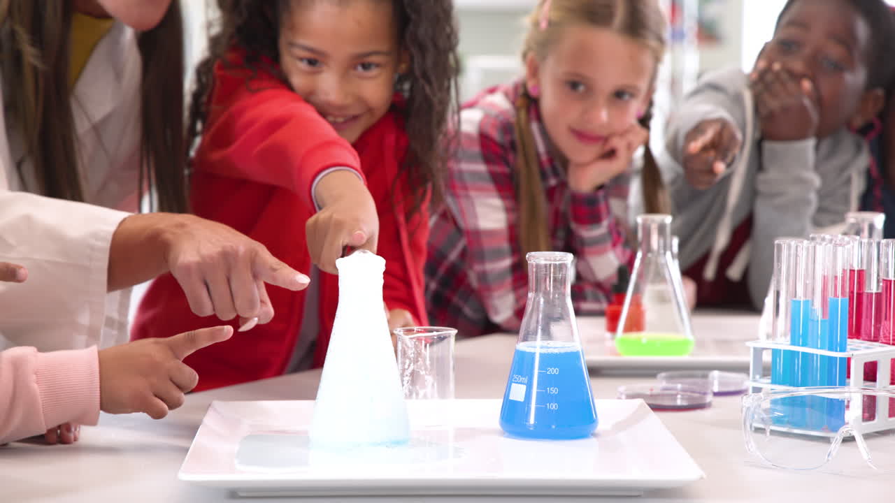 Teacher and students enjoying science experiment with colorful liquids in classroom