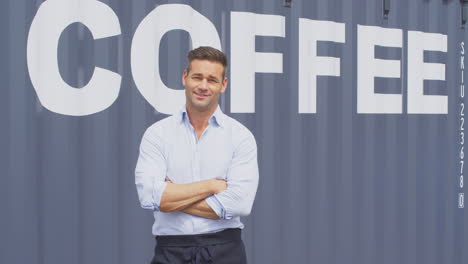 portrait of male owner of coffee shop or distribution business standing by shipping container