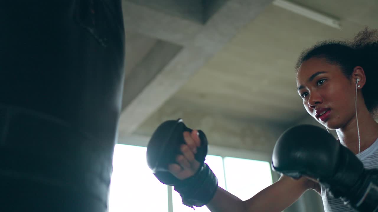 4K Healthy African woman listening to the music from earphones while do boxing exercise at gym.