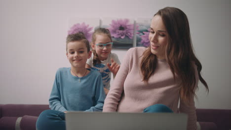 woman with children video call on laptop. girl waving hand video conversation