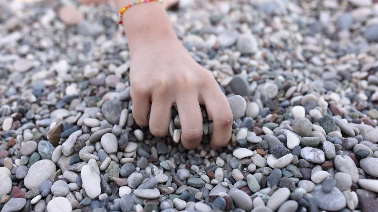 Hand touching pebbles on a beach