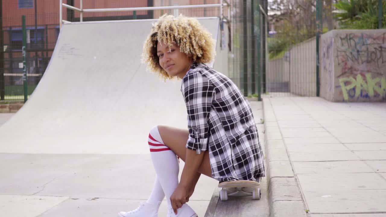 Young woman sitting on her skateboard at the rink