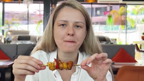 woman eating grilled skewers in a restaurant