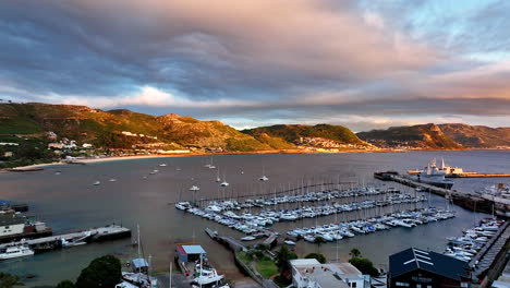 Aerial-cinematic-drone-sunrise-Simon's-Town-naval-sail-boat-marina-fishing-small-quite-city-Cape-Town-South-Africa-early-sunlight-clouds-Table-Mountain-Fish-Hook-Muizenberg-penguins-forward-movement