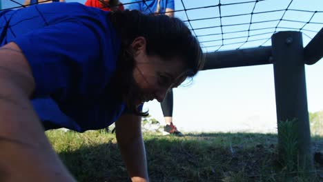 Teammates-applauding-woman-while-crawling-under-net