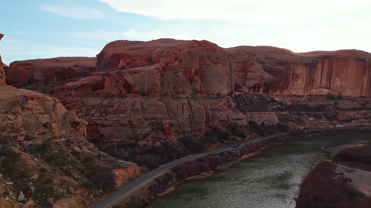 Breathtaking aerial establishing overview of road along steep sandstone cliffs in Moab deep canyons, layered rock formations and open terrain