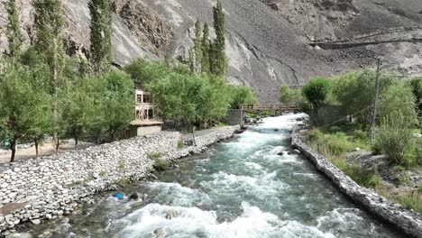 un lago de manantial natural en el área de pakistán, el lago skardu mantoka, el agua que fluye entre las paredes de piedra y las casas adyacentes