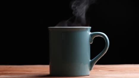 close up hot coffee cup with nature steam smoke of coffee on wooden table, black background with copy space. coffee and tea drink concept.