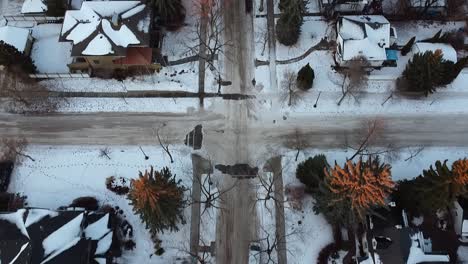 3-4-Aerial-dolly-roll-over-winter-luxury-residential-housing-area-twilight-where-the-sunsets-and-its-rays-on-the-bare-icy-tree-tips-following-a-white-unmarked-van-headed-home-on-a-snow-covered-street