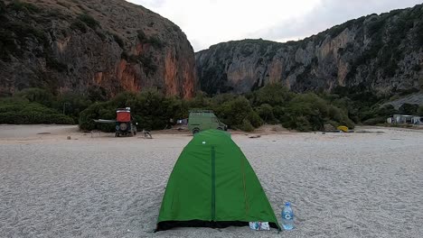 una vista de una carpa parada durante la noche en la hermosa playa entre otros autos de camping