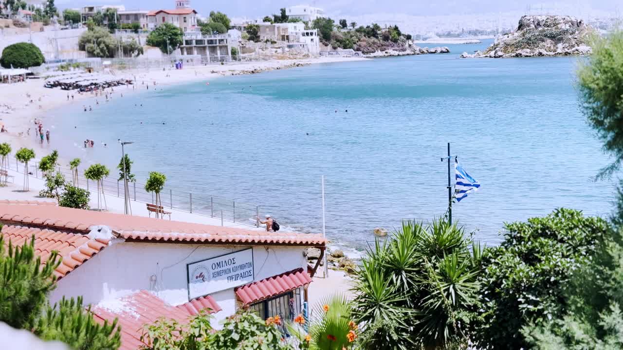 Yunan bayraklı Pire plajında yazın yüzen insanlar