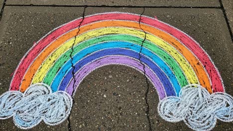 vibrant rainbow chalk drawing spanning across a concrete surface with fluffy white clouds enhancing the colorful artistic expression