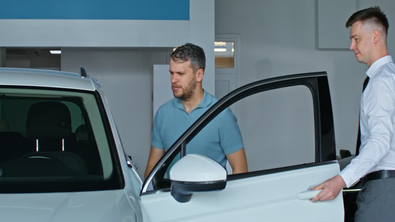 vendedor de coches mostrando el coche al cliente en la sala de exposiciones