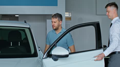 vendedor de coches mostrando el coche al cliente en la sala de exposiciones