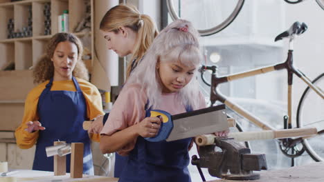 team of female trainees in workshop learning how to assemble hand built bicycle frame together