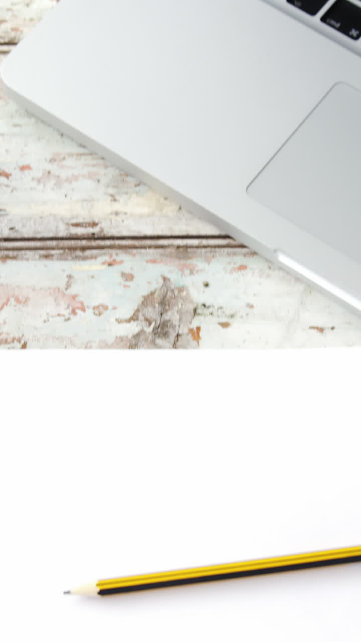 Tazza di caffè, laptop, telefono cellulare, carta, matita su un'asse di legno.