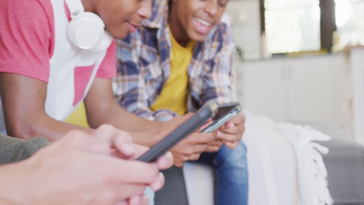 Video of happy diverse male teenage friends using smartphones, slow motion