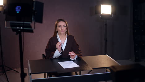 beautiful female reporter talks and gestures on camera. blog or program footage in studio.