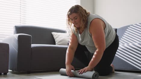 caucasian woman keeping fit and rolling up yoga mat