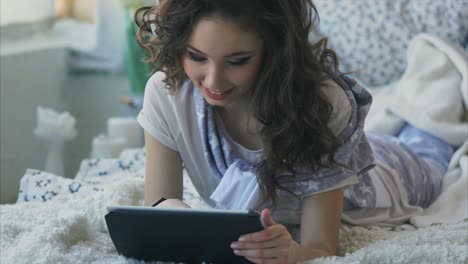young woman relaxing on bed with tablet