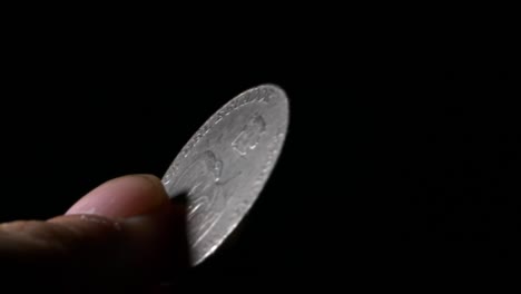 person rotating ecuador currency coin closeup holding foreign cash