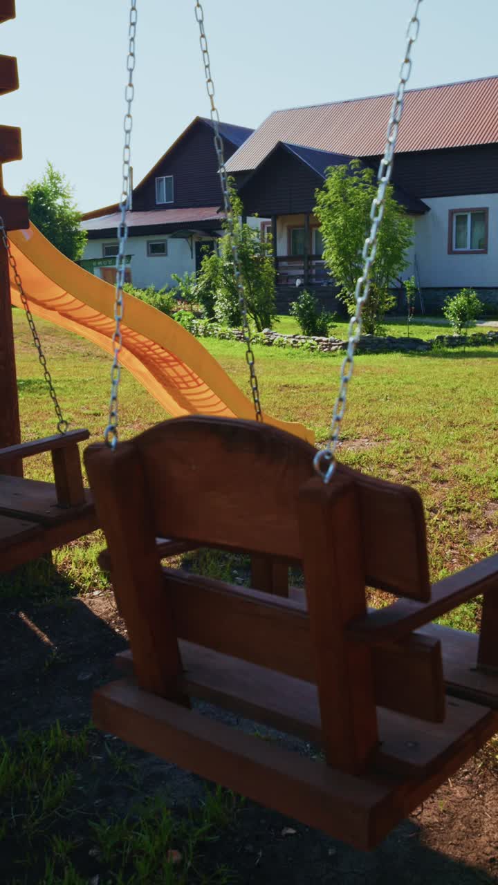 Empty Wooden Swing Set Gently Swings in a Sunny Backyard