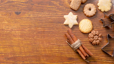 composición de decoraciones navideñas con canela, galletas y piñas sobre fondo de madera