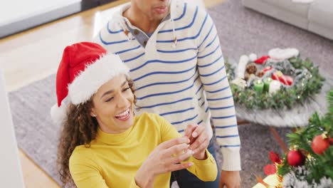 Video-of-happy-diverse-couple-decorating-christmas-tree-at-home