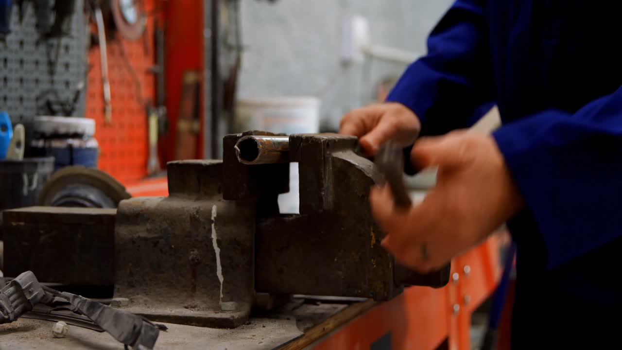 Mechanic using bench vises in garage 4k