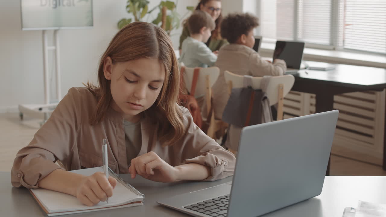 Kaukasisk jente som bruker laptop i klasserommet