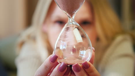 a woman looks at an hourglass