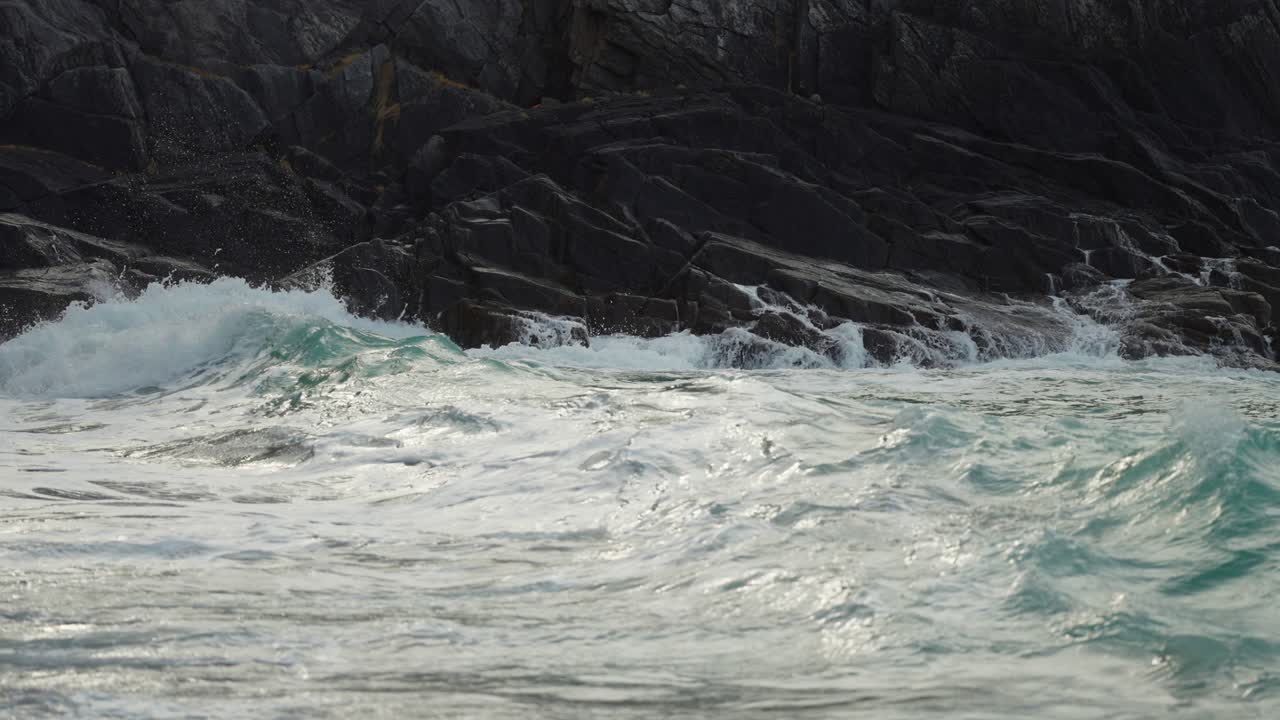 파도가 바위에 부딪치고 모래사장에 쏟아지는 클로즈업 샷