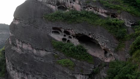 Cave-rock-formation-in-mountainside,-China-karst-mountain-landscape,-4K-aerial