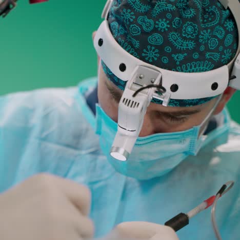young doctor with a microscope on his head. hands of medical specialists during operation on the surgeon's face background. close-up.