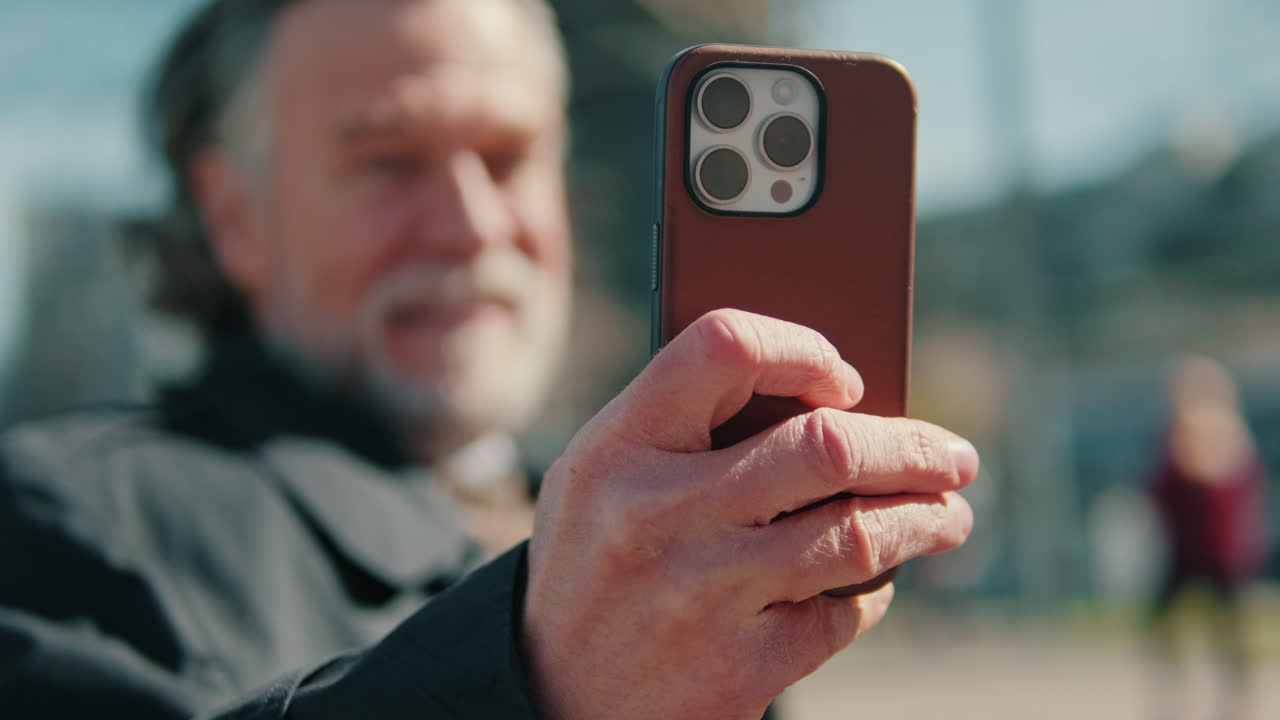 Smiling Man Browsing on Phone in the City, focus on the phone