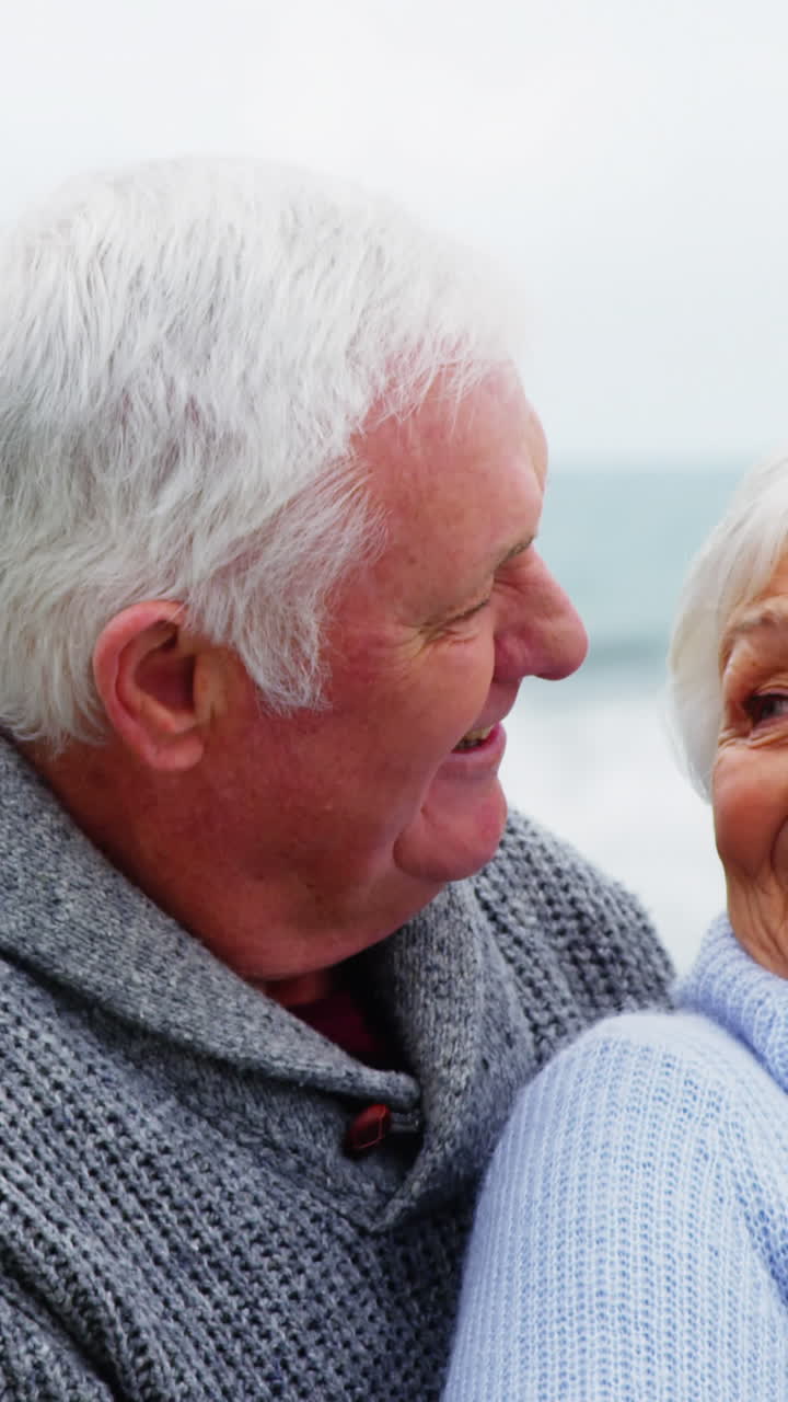 Coppie senior che si abbracciano sulla spiaggia