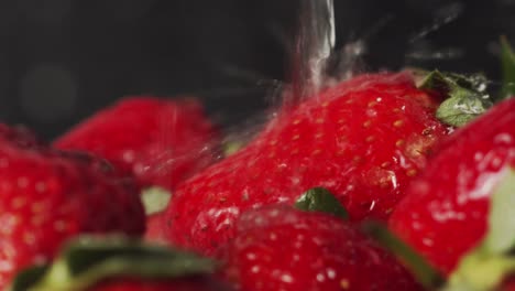 kitchen tap water splashing onto red strawberries close