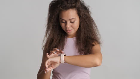 Caucasian-curly-haired-woman-checking-notifications-on-smartwatch.