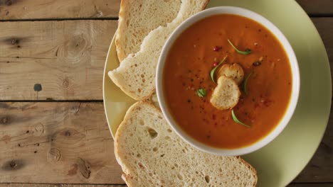 video of cream tomato soup in bowl on wooden table with bread