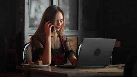 happy businesswoman sitting at the table and talking on the phone in cafe. looking away