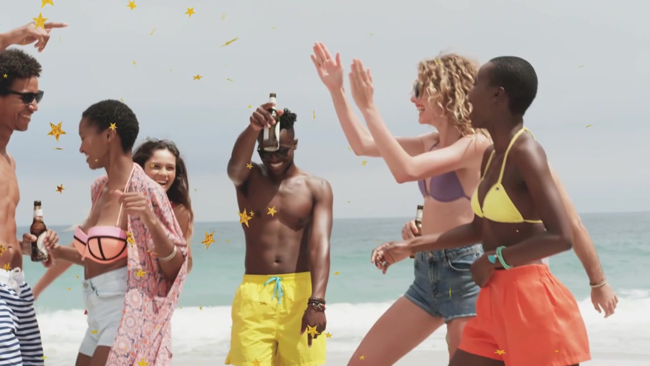 Group raising bottles, confetti falling around, celebrating and walking to cam on beach for travel