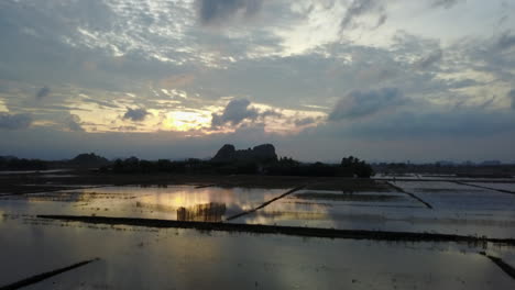 n amazing view of sunset reflecting in a flooded agricultural area in ninh binh, vietnam, on a cloudy day. the still water creates a mirror image of the dramatic sky and landscape.