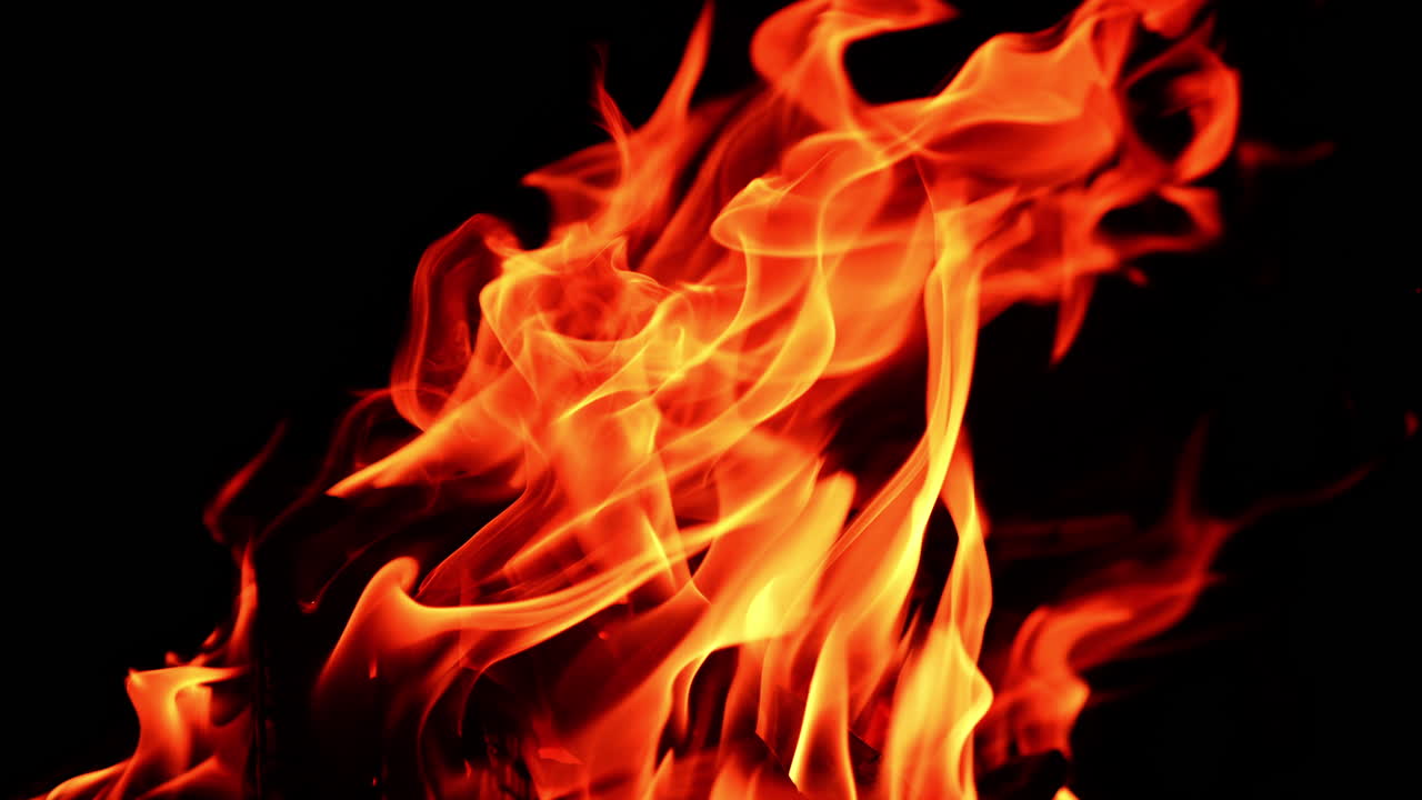 Hot flames of bonfire leaning to the right. Isolated view of campfire burning at night. Close up.